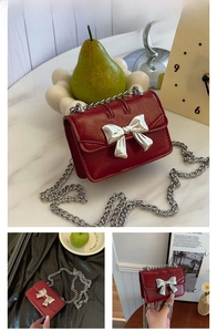 Detailed view of a red mini flap bag with a silver metal butterfly and chain strap