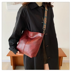 Chic burgundy tote bag with ethnic pattern strap shown on model in modern setting