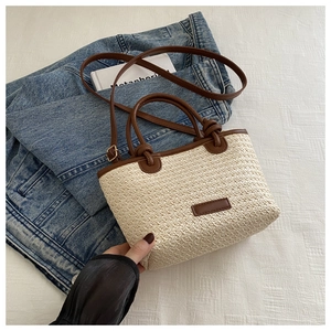 Détail d'un sac en paille tissée avec garniture en cuir brun sur veste en jean