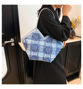 Dettaglio borsa tote in denim intrecciato azzurro con bordi sfrangiati e scollo a V