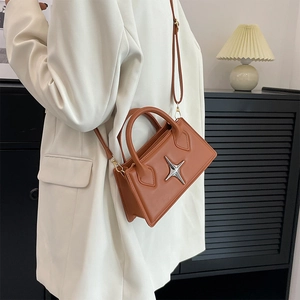 Brown square crossbody bag with star hardware shown on a model in a white suit