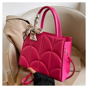 Close-up of rose red tote bag with quilted pattern and decorative silk scarf detail