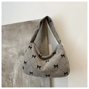 Detail of light gray corduroy shoulder bag with black bow embroidery and quilted pattern