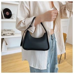 Detailed view of black hobo bag with gold zipper and smooth matte finish on a model
