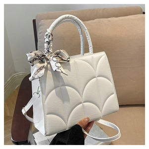 Detalle de bolso blanco acolchado con costuras de concha y asa con pañuelo de seda decorativo
