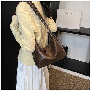 Detail of the brown leather shoulder bag featuring a unique braided strap and hobo shape