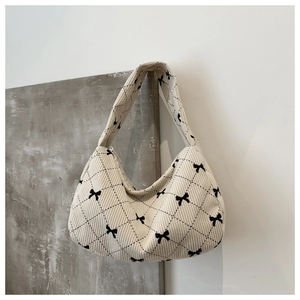 Detail of corduroy shoulder bag featuring black bow patterns and quilted texture