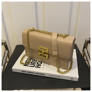 Detail of beige leather crossbody bag with vintage gold square lock and chain strap