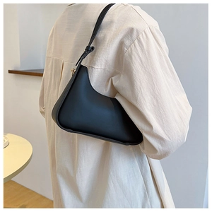 Detail of minimalist black leather underarm bag with golden hardware and sleek silhouette