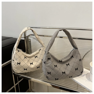 Close-up of hobo shoulder bags with bow patterns on a modern metal display shelf
