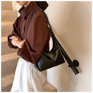 Detail of black underarm bag with unique braided shoulder strap and leather texture