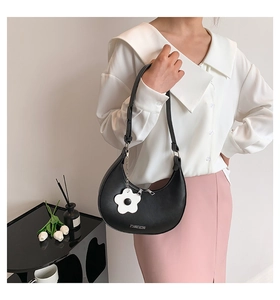 Detail of black crescent shoulder bag with white flower charm and JIASHIQING logo