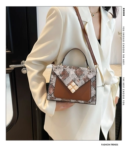 Close-up of snake print leather crossbody bag with decorative jewel clasp and brown strap