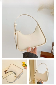 Detail view of cream white crescent underarm bag with smooth leather and gold buckle