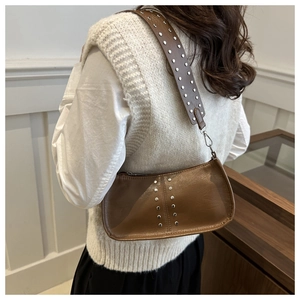 Détail du sac vintage en cuir marron avec rivets argentés et large bandoulière décorative