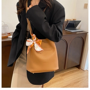 Detail of brown lychee grain leather bucket bag with silk scarf and FASHION & BAG embossing