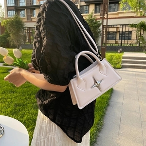 Close-up of cream square bag with silver star buckle and adjustable crossbody strap