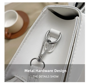 Macro detail of silver-tone metal lobster clasp and D-ring on white leather handbag strap