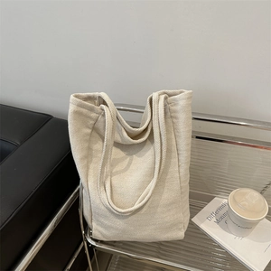 Grand sac cabas en toile à chevrons beige posé dans un décor urbain moderne