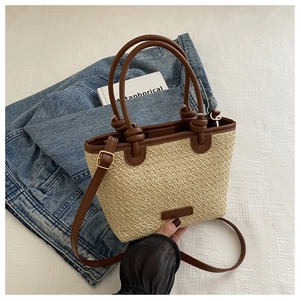 Vue de dessus du sac cabas en paille tissée avec anses en cuir marron sur fond denim