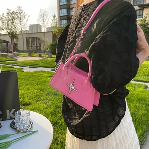 Pink crossbody bag with silver star ornament worn by a model in an outdoor setting