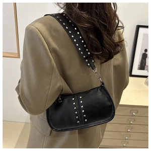 Détail d'un sac d'épaule noir en cuir avec rivets argentés et large bandoulière réglable
