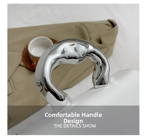 Detail shot of a minimalist white leather handbag with a unique silver metal handle