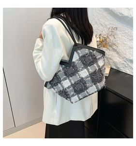 Dettaglio della borsa tote in tweed con frange e manici in pelle nera su una modella