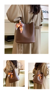 Detail view of large brown leather bucket bag with textured finish and floral scarf accessory