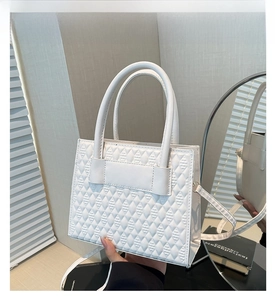 Detail of white quilted handbag showing textured rhombic pattern and side profile
