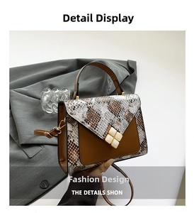 Detail of snake skin pattern stitching and gold magnetic clasp on the crossbody bag