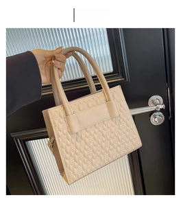 Detail of khaki handbag with quilted rhombus stitching and sturdy dual handles