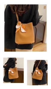 Detail of brown litchi leather bucket bag featuring a decorative printed silk scarf handle
