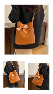 Detail of brown leather bucket bag with fashion print and decorative floral scarf
