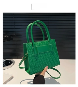 Detail of green handbag showing 3D geometric embossed texture and round handle