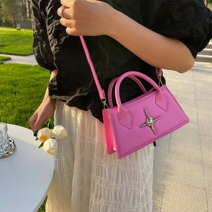 Pink rectangular crossbody bag with silver star badge shown on a woman in outdoor setting