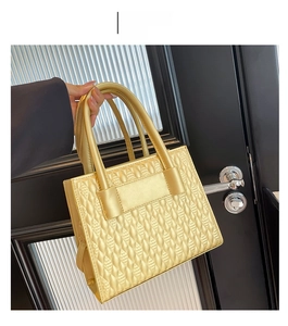 Detailed macro view of the gold embossed leather texture and handle on a stylish handbag