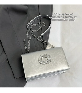 Détail du sac argenté avec texture craquelée métallique et boucle en strass