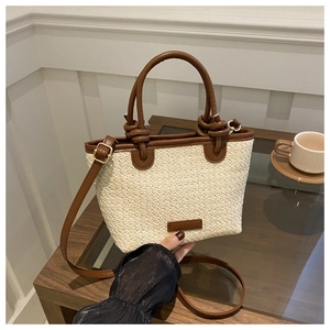 Détail du sac cabas beige tressé avec poignées en cuir marron et bandoulière réglable