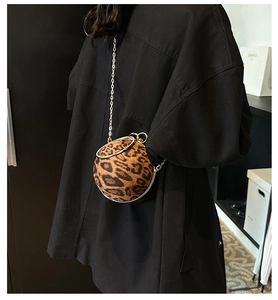 Close-up of leopard print sphere bag with gold metal handle and chain strap on model