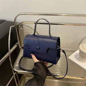 Piccola borsa a mano blu navy in pelle testurizzata con fibbia tonda e tracolla