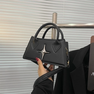 Detail of a black leather square handbag featuring a silver star buckle and hand carry style