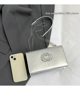 Détail du sac en cuir argenté avec boucle en strass et comparaison de taille avec mobile