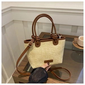Détail du sac cabas en paille avec anses nouées en cuir marron et bandoulière amovible