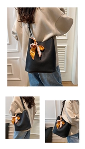 Detail of black litchi grain leather bucket bag with elegant printed silk scarf accessory