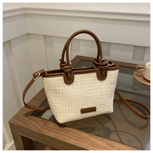 Détail d'un sac cabas en paille crème avec anses en cuir marron et nœuds élégants