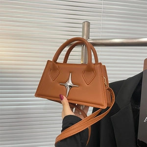 Detail of a brown trapezoid leather handbag with a silver star ornament and round handles
