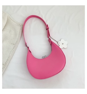 Detail view of pink crescent hobo bag featuring matte faux leather and a white flower charm