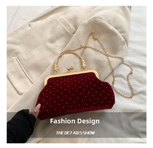 Detail show of red velvet shell bag with white polka dots and gold metal handle