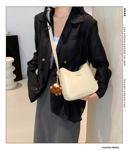 Detail of off-white PU leather hobo bag with gold Fashion plate and brown plush charm
